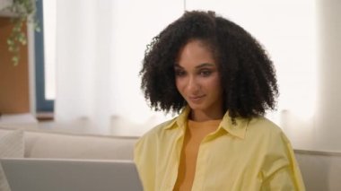 Mutlu gülümseyen Afro-Amerikalı iş kadını etnik iş kadını ev yapımı bilgisayar projesinde çalışıyor internetten internet üzerinden internet alışverişi öğreniyor ve laptopta oyun oynuyor.