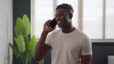 Afro-Amerikalı, etnik, neşeli, hippi, ev banyosunda konuşan, cep telefonuyla konuşan, otel banyosunda sohbet eden, uzak mesafede, mutlu bir erkek, sabah cilt bakımına bakıyor.