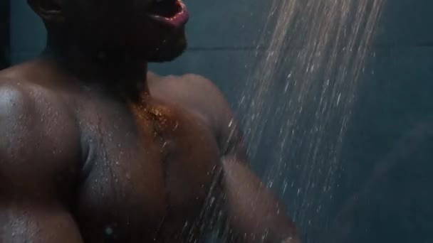 非洲裔美国人赤裸裸的湿男人在淋浴中跳舞听音乐少数民族赤裸裸的性感肌肉运动员唱歌滑稽的舞步在黑暗的浴室男厕早上洗澡身体热的落水 — 图库视频影像