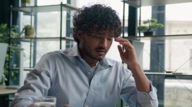 Aşırı çalışmaktan yorgun düşmüş Arap işadamı ofis çalışanı yönetici hasta işveren CEO dizüstü bilgisayarla çalışıyor bitkin erkek iş adamı baş ağrısı çekiyor.