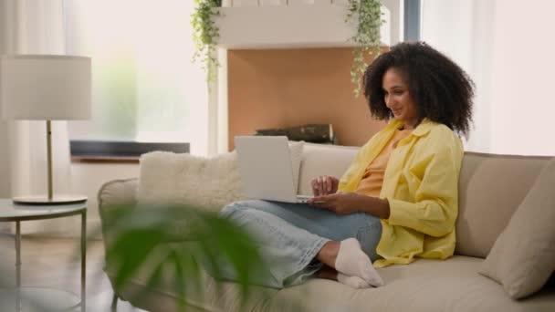 非洲裔美国女性房主在沙发上轻松地使用笔记本电脑在线聊天上网上网上网学习在家里的电脑女商人自由职业女商人的电子学习 — 图库视频影像
