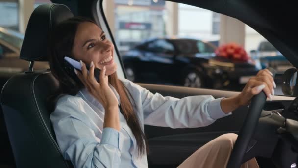 ハッピーコーカサス成功したビジネスマン 話す携帯電話の通話友好的な会話の喜びの女性は自動車の高級車の話すスマートフォンを購入してレンタルする自動車ショップの賃貸サービスで新しい車に座ります — ストック動画