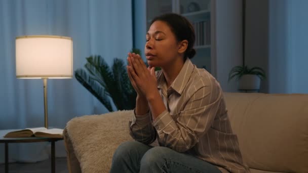 忧心忡忡心烦意乱的非洲裔美国妇女遭受着压力祈祷焦虑心理问题悲伤孤独地躺在沙发上晚上回家想想抑郁症意外怀孕 — 图库视频影像