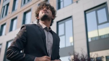 Kendine güvenen iş adamı etnik Hintli işadamı Müslüman erkek şirket CEO 'su Arap girişimci şehir dışına çıkıyor ofis binası yakınlarına gidiyor gökdelenlere bakıyor.