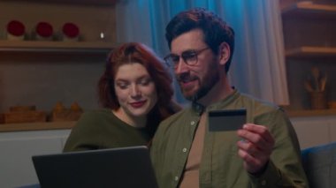 Mutlu Kafkasyalı evli çift karı koca, elektronik bankacılık uygulaması aile bütçesi kullanılarak akşam güvencesi ödemesi yapılan internet mağazasında dizüstü bilgisayarla uzaktan ödeme yapıyorlar.