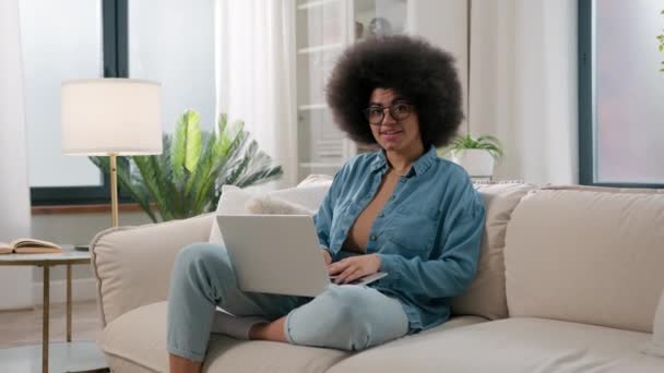 アフリカ系アメリカ人女性エスニックガールホームソファソファフリーランサーの学生ユーザーとPcインターネットのオンラインソーシャルメディアを使用して勉強ラップトップコンピュータを使用して親指を示す推奨配信サービス — ストック動画