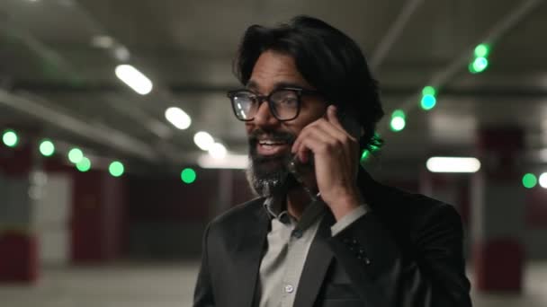 感情的なインドの男性のビジネスマン起業家 地下駐車場で携帯電話で話す 回答ビジネスコール スマートフォン通話タクシー男従業員 電話でコミュニケーション — ストック動画