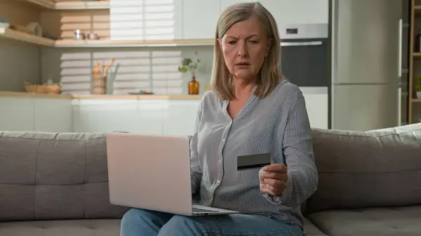 Mature caucasian woman retired senior lady dissatisfied client experiencing problem on laptop with online payment failure bank credit card error mistake unsuccessful transaction trouble wrong password