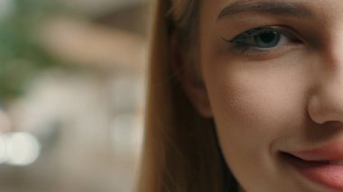 Kırpılmış yarım surat, gülümseyen beyaz Avrupalı kız gen z genç güzellik yüz detaylı makyaj ruj göz kalemi kameraya bakarken gülümseme göz oftalmolojisi boş kopya alanı