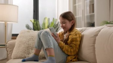 Mutlu gülümseyen beyaz kız öğrenci. Akıllı telefonuyla mesaj yazıyor. Sosyal medya sohbeti yapıyor. Eğitim için öğrenme uygulamasını cep telefonuyla sanal oyun oynuyor.