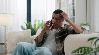 Üzücü üzüntü, endişeli Afrikalı Amerikalı endişeli, çift ırklı, stresli adamın evdeki telefon konuşması, kötü haber, şok, akıllı telefon, olumsuz konuşma.