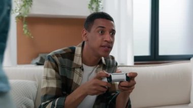 Evde oyun oynayan Afrikalı Amerikalı oyuncu oyun konsolu olan adam sanal dövüşçü kızla eğleniyor. Joystick almaya çalışıyor. Komik dövüş oyunları bağımlılığı oynamak istiyor.