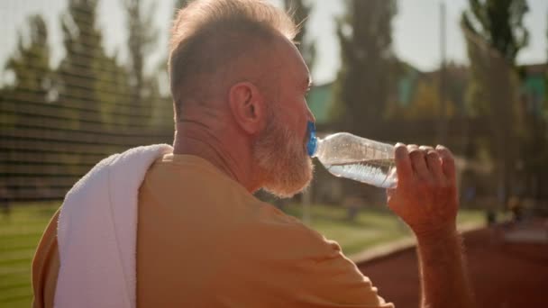 Rückansicht Alte Männliche Sportler Gehen Stadion Freien Trinken Kaltes Wasser — Stockvideo