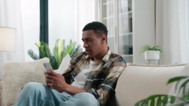 Afro-Amerikalı etnik adam sosyal medyayı okuyor cep telefonuyla sohbet ediyor kötü haberler okuyor sorununu kaybediyor cep telefonu reddetme mesajından rahatsız oluyor.