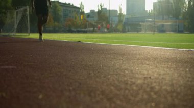 Kırpılmış şutlu sporcu bacakları bilinmeyen bir stadyumda koşuyor Afrikalı Amerikalı sporcu koşucu koşucu koşucu antrenmanı için maraton kardiyo antrenmanı için koşuyor güneşli bir sabahta şehir dışında koşu sporu yapıyor.