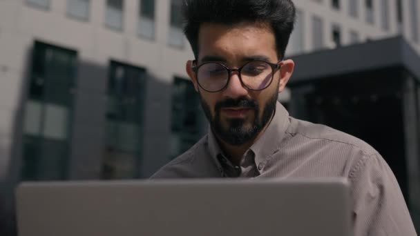 インドのアラビアの大人の男ビジネス雇用主 ラップトップのオンライン ネットワーキング遠隔フリーランスの仕事 外のオフィス会社の建物の男性のビジネスマンの笑顔 コンピュータのEラーニングの屋外で — ストック動画
