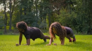 Spor yapan çeşitli Arap erkekler sabah sporu yapan beyaz kadın şehir parkında spor yapıyor sporcu güçlü sporcu kadın vücut geliştiriciler çimlerin üzerinde egzersiz yapıyor.