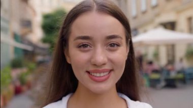 Kentin dış kesimlerinde gülümseyen beyaz kadın kameralı dişlek gülüşlü kafe mutlu kadın portresi dışarıda pozitif yaşam tarzı modeline bakarken eğleniyor.