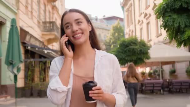 ヨーロッパの白人女性ビジネスウォーキング街路 笑顔の笑顔の女の子は 携帯電話をチャットする外でコーヒーを楽しんで楽しむ 幸せなビジネスレディー カジュアルな外出 — ストック動画