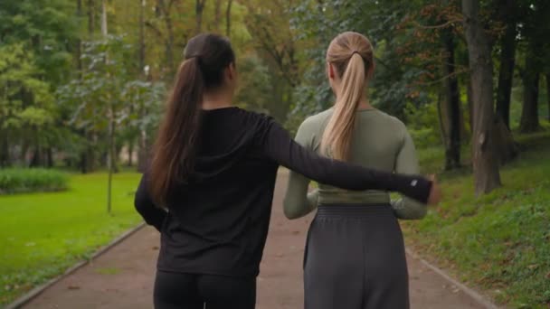 バックビュー2 認識できないスポーツガール女性 スポーティな服で女性の友人 都市公園のアスレチックスポーツ女性は抱擁女性チームの友情サポートアクティブな健康的なライフスタイル — ストック動画