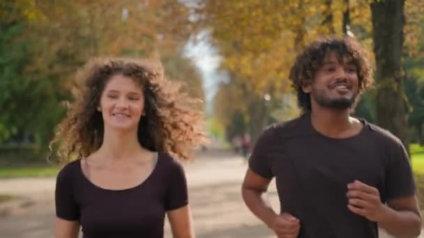 城市秋季公园多种族健身夫妇一起进行户外运动快乐的两个跑步者高加索女人和阿拉伯男人健康的运动员在外面进行体育活动有氧运动的挑战 — 图库视频影像