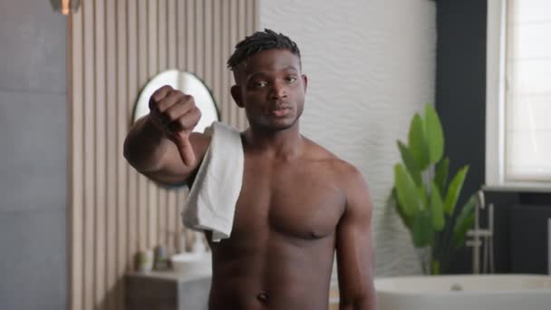伤心而不满意的非洲裔美国男人在浴室里惹怒了一丝不挂的30多岁的英俊男人男模展示大拇指倒了坏结果不同意不喜欢没有任何迹象表明在浴室里拒绝低分化妆品 — 图库视频影像