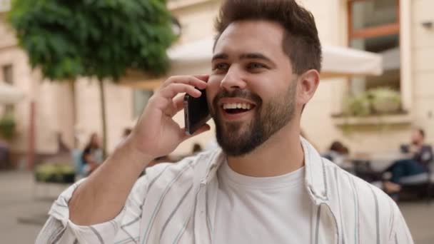 コーカサス人の男性のビジネスマンは 笑う男のカジュアルなトーク携帯電話のビジネスコール屋外で笑う携帯電話を話す 幸せな男は 外の街路でニュースの友人スマートフォン通信を議論 — ストック動画