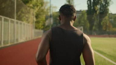 Arkaya bakan Afro-Amerikan sporcu açık hava şehir stadyumunda koşuyor tanınmayan erkek koşucu erkek koşucu sabah maraton koşucusu yarış sporu antrenmanı dışında koşuyor.