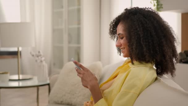 아프리카계 미국인 여자는 거실에서 소파에 모바일 비디오 게임을 스크롤 스마트 — 비디오