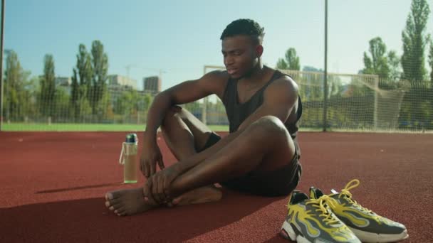 伤心的非洲裔美国人男子运动员赛跑选手足球运动员在体育场上受伤脚痛 肌肉抽筋 运动创伤 锻炼腿受伤 — 图库视频影像