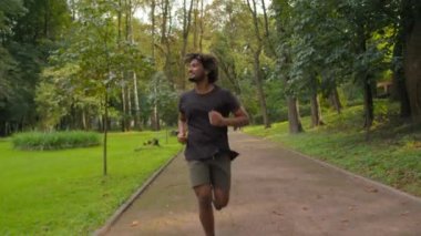Mutlu sporcu Arap erkek koşucu sabah koşusu şehir parkında açık havada koşuyor sağlıklı aktif spor yaşam tarzı fitness sporcusu spor koşucusu spor koşusu antrenmanı kardiyo antrenmanı