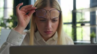 Kafkasyalı iş kadını kadın iş kadını laptop ekranına bakarak gözlüklerini çıkarıyor. Ofisteki bilgisayarın aşırı çalışmasından sonra görüşü bulanıklaştırıyor. Gözlük gözlüğündeki kötü görüntüyü kontrol ediyor.