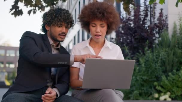 男性专业导师阿拉伯印度男人帮助女经理非洲女人教实习生培训新员工在办公室附近的城市解释在线商务服务公司的笔记本电脑 — 图库视频影像
