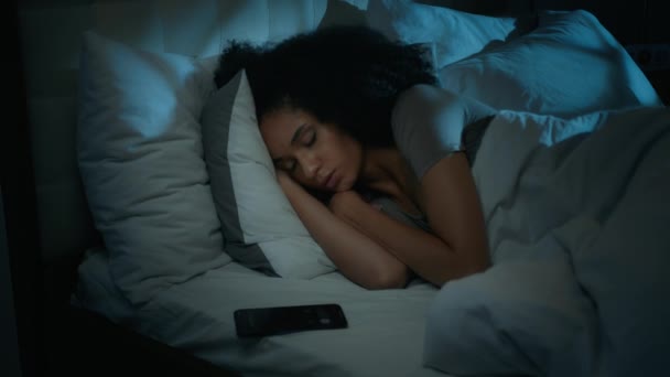 アフリカ系アメリカ人女性 ベッドで寝ている 夜遅くに電話で目覚めると警報時計で目覚め 通話通知 夜中にイライラしたイライラした女の子が目を覚ます リングスマートフォンをオフにする — ストック動画