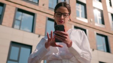 Kafası karışmış Kafkas bir kadın cep telefonu kullanıyor şehir merkezindeki kız iş kadını caddelerini arıyor sosyal medyada geziniyor akıllı telefon konumlandırma navigasyonu kullanıyor iş merkezini araştırıyor.