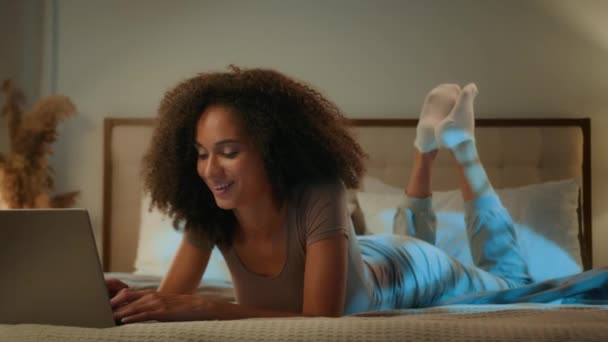 笑顔の幸せなアフリカ系アメリカ人女性若い遺伝子Z 20Sガール ラップトップのインターネットチャット中毒ショッピングアプリ睡眠障害夜眠眠気不眠で夜のベッドルームでPcコンピュータを使用して — ストック動画