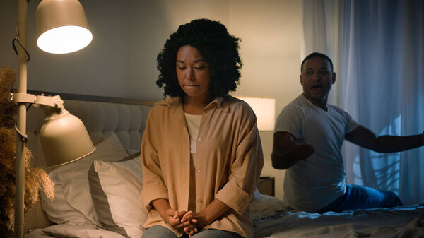 Couple quarrel sad African American woman feel desperate jealous husband angry man shouting accusing screaming yelling talking to wife breakup marriage divorce in bed night problem unwanted pregnancy