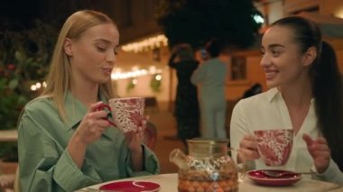 Avrupalı Kafkasyalı genç kadınlar ellerinde fincanla çay içerek sohbet ediyorlar restoranın dışında gülümseyen şehir kafeteryasında eğleniyorlar mutlu bayanlarla buluşuyorlar dinlenme yeri hafta sonu sokak