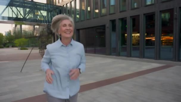 都市の朝に働くために走っている白人シニア幸せな女性 ジョギング屋外高齢女性 Ceo 笑顔の古いビジネスウーマンジョブ活動 ビジネスミーティングのために遅くオフィスビルに走る — ストック動画