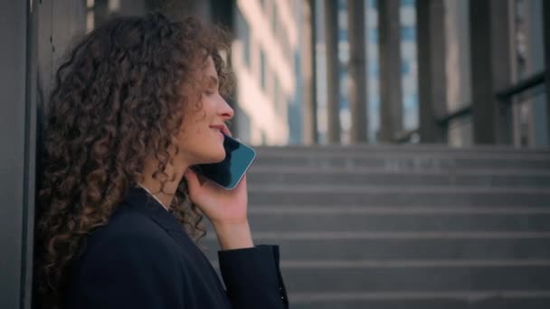 コカシアのビジネスウーマン雇用主女性マネージャーガール 若いビジネス女性起業家の外のオフィスの建物の壁の近くのスマートフォン話すスマートフォン 屋外のクライアントと話す モバイル通話チャット — ストック動画