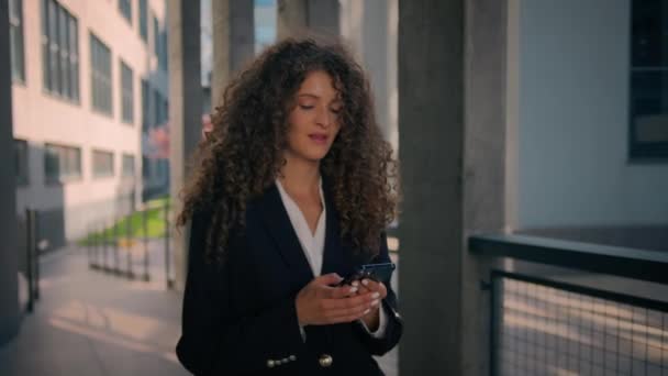 スマートフォンの若いビジネスマンと街路を歩く笑顔の白人女性ビジネスガールは 同僚のモバイル会話女性雇用主女性がダウンタウンの外で電話のコミュニケーションを話すことを呼び出します — ストック動画