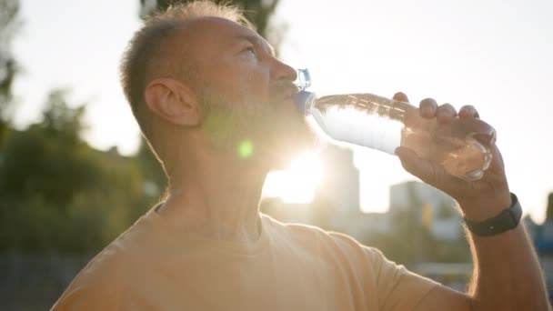 Großaufnahme Älterer Mann Trinkt Klares Mineralwasser Morgensonne Strahlen Durstigen Männlichen — Stockvideo