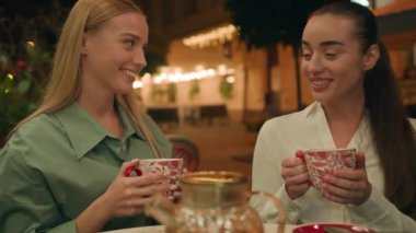 İki Kafkas Avrupalı mutlu kadın çay kafesi caddesinde akşam vakti sohbet ediyorlar gülüşmeler gülüşmeler restoran rahatlama toplantısını tartışıyorlar yaz tatilinde birlikte eğleniyorlar.