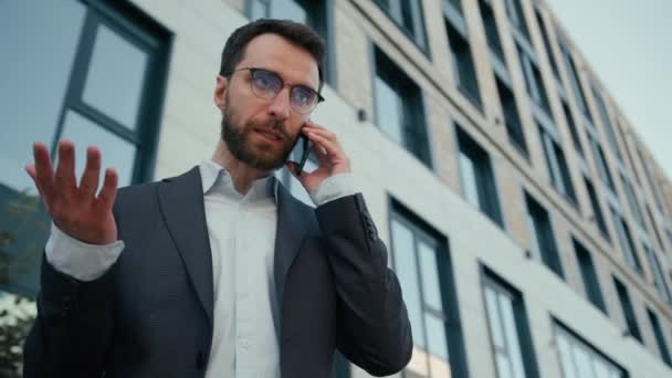不満な感情コーカサス成人男性男性ビジネスマンは 雇用主起業家オフィスの労働者にショックを与えました 屋外で携帯電話を話す 信じられないほどのニュースビジネス問題 都市のスマートフォン会話 — ストック動画