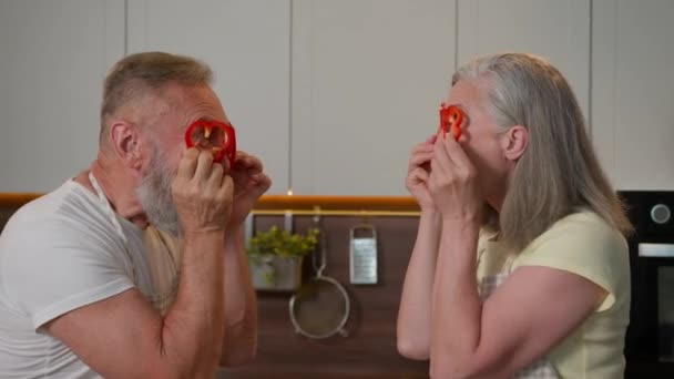 有趣而快乐的退休老奶奶白种人爷爷老太太一起玩乐做红辣椒眼镜圈中年妻子丈夫老祖父母在厨房煮新鲜蔬菜 — 图库视频影像