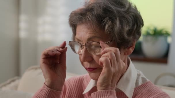 生病不健康的白种人老妇人感到不适模糊的视力老年女性摘下眼镜感觉眼力紧张按摩烦躁干眼痛眼镜头疼 — 图库视频影像