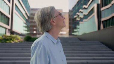 Gülümseyen, düşünceli yetişkin, yetişkin, beyaz kadın, orta yaşlı, yaşlı, başarılı iş kadını, başarılı, yaşlı, neşeli, işveren, gözlüklü, açık hava fotoğraflarında gözlüklü bir CEO.