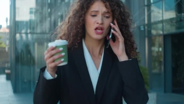 怒っている怒っている狂ったビジネスマンは 屋外で携帯電話を話すと ストリートコーヒーを飲むカフカシアのビジネス女性は 否定的なスマートフォン通話の問題を主張し 街の紛争の叫びを歩くストレス — ストック動画