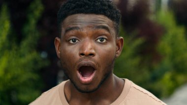 Çift ırklı insanın ağzını kapatarak şok edici bir tepkiyle inanılmaz bir yüz ifadesi şaşkına dönmüş afallamış şaşırtıcı erkek yüzü beklenmeyen haberler Afro-Amerikalı adamın şehirde harikalar yaratmasına şaşırmış.