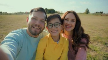 Mutlu gülümseyen beyaz aile babası anne oğul çocuk cep telefonu pozu veren çocuk kırsal alanın dışında selfie çekiyor. Ebeveynlik tatilinde ebeveynler doğayı dışarı park ederler.